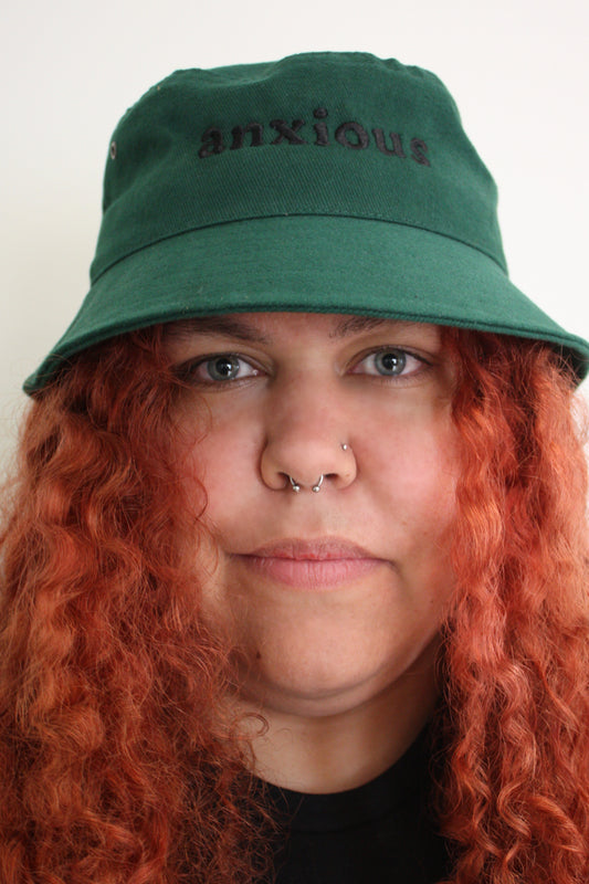 Bucket of Anxiety - Cooked Concepts (the best hat for sun protection, but a warning to others your anxiety is a thing. Bottle green bucket hat with black embroidery saying ANXIOUS)